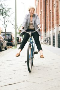 Trendy young woman having fun with her bike in city streets.