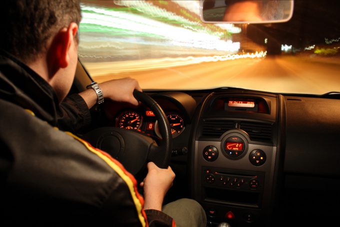 The photo shows a man driving a sports car